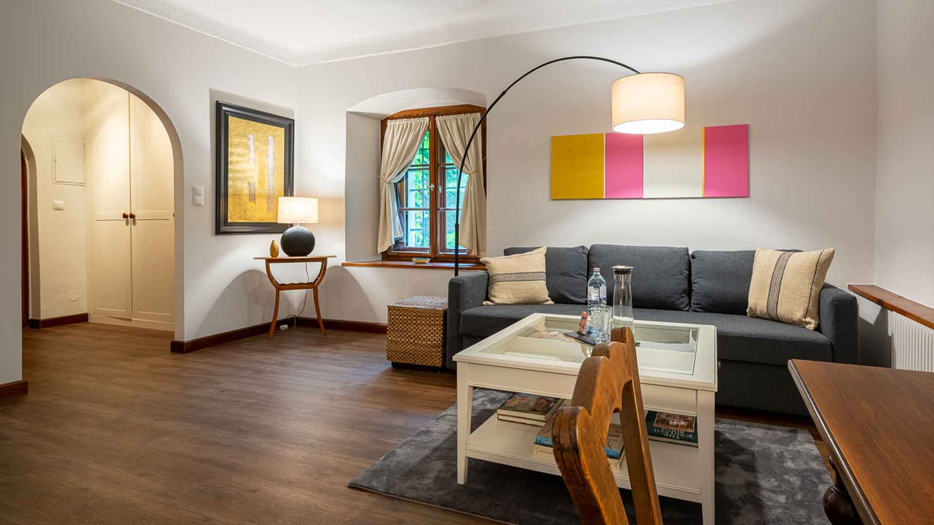Gemütlich eingerichteter Wohnbereich eines Gästezimmers mit Sofa, Lampe, Couchtisch und stilvoller Dekoration.
