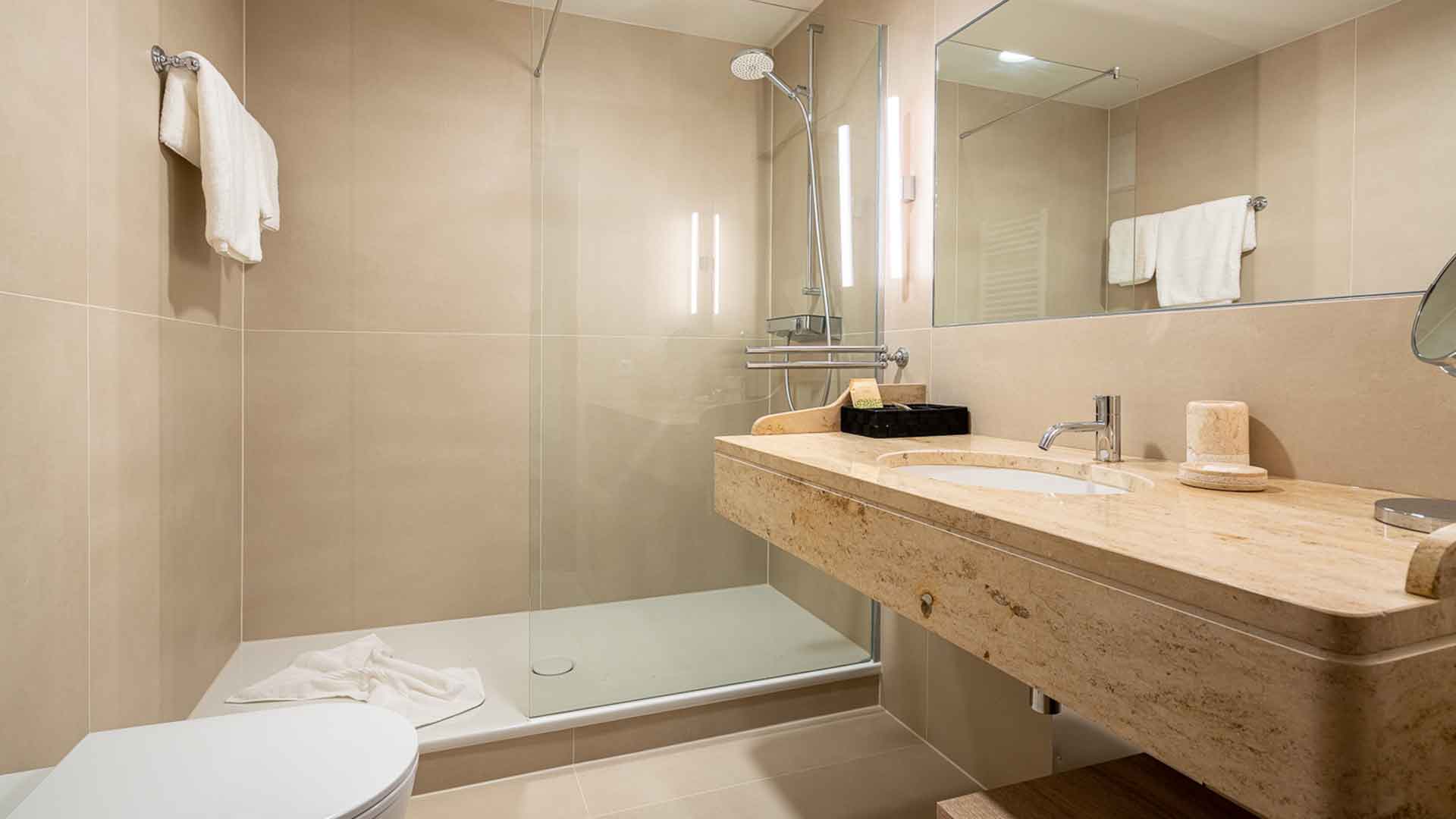 Modernes Badezimmer mit großer begehbarer Dusche, Marmorwaschtisch und klarer Linienführung.