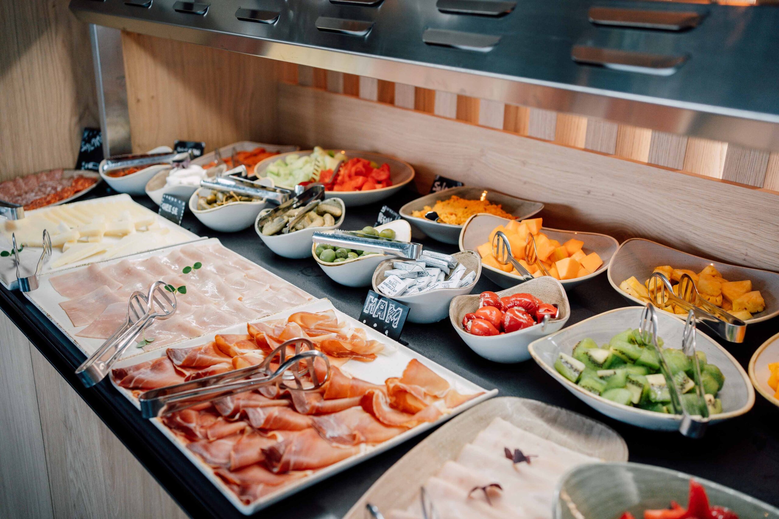 Kaltes Frühstücksbuffet mit einer Auswahl an Aufschnitt, Käse, frischem Obst und eingelegtem Gemüse.