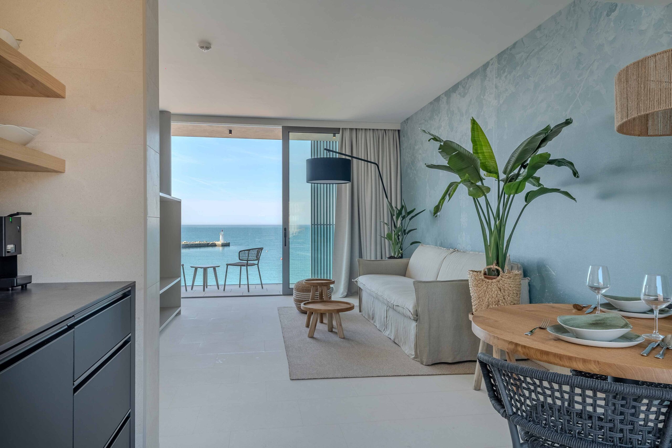 Helles Apartment mit Wohn- und Essbereich, Balkon mit Meerblick und Blick auf einen Leuchtturm am Hafen.