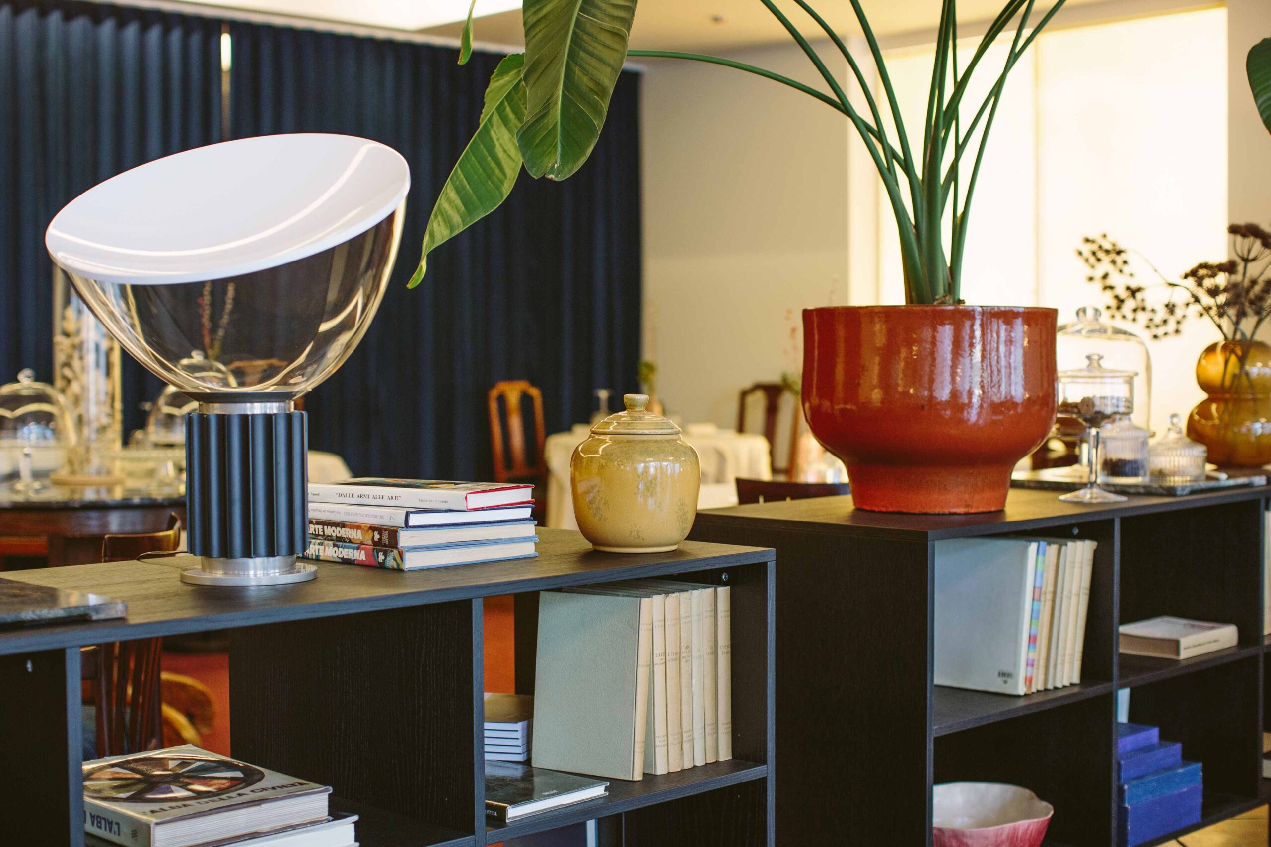 Ein stilvolles Interieur mit modernen Regaleinheiten und einem einladenden Essbereich. Auf den Regalen sind dekorative Objekte und Bücher zu sehen, während sanfte Beleuchtung eine gemütliche Atmosphäre schafft.