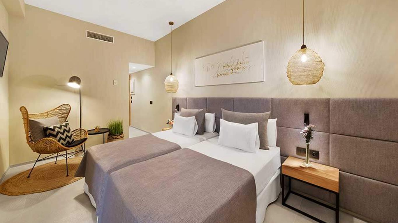 Modern eingerichtetes Hotelzimmer mit zwei Einzelbetten, sanften Naturtönen, geflochtenem Sessel und hängenden Lampen.