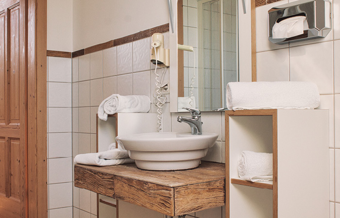 Waschbecken mit Holzablage, Handtücher auf Ablage und Regal, Wandspiegel und Wandtelefon in Badezimmer