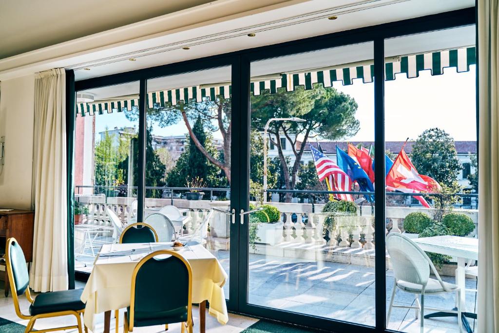 Restaurantbereich im Ambassador Palace Hotel mit Blick auf die Terrasse und gedeckten Tischen.