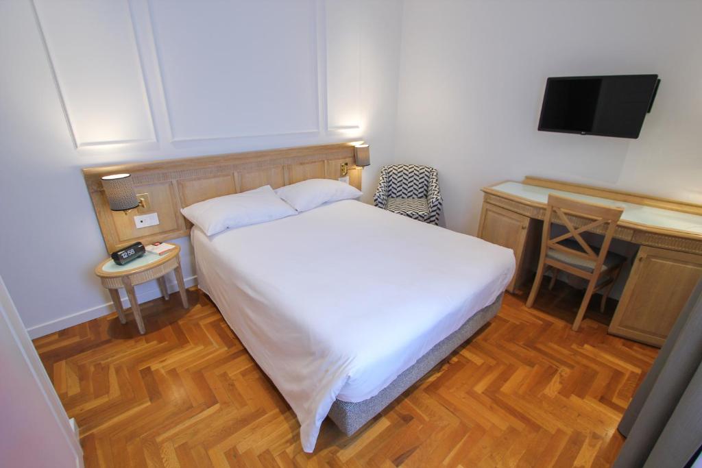 Klassisches Hotelzimmer im Ambassador Palace Hotel mit Doppelbett, Schreibtisch und Holzboden.