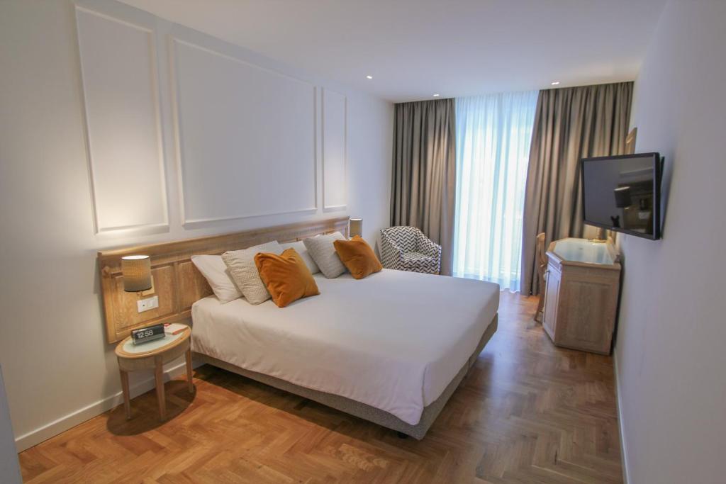 Modernes Doppelzimmer im Ambassador Palace Hotel mit Holzboden, Fernseher und bodentiefen Vorhängen.