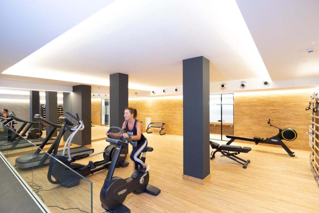 Fitnessraum im Ambassador Palace Hotel mit Cardio-Geräten, Trainingsflächen und Holzoptik.