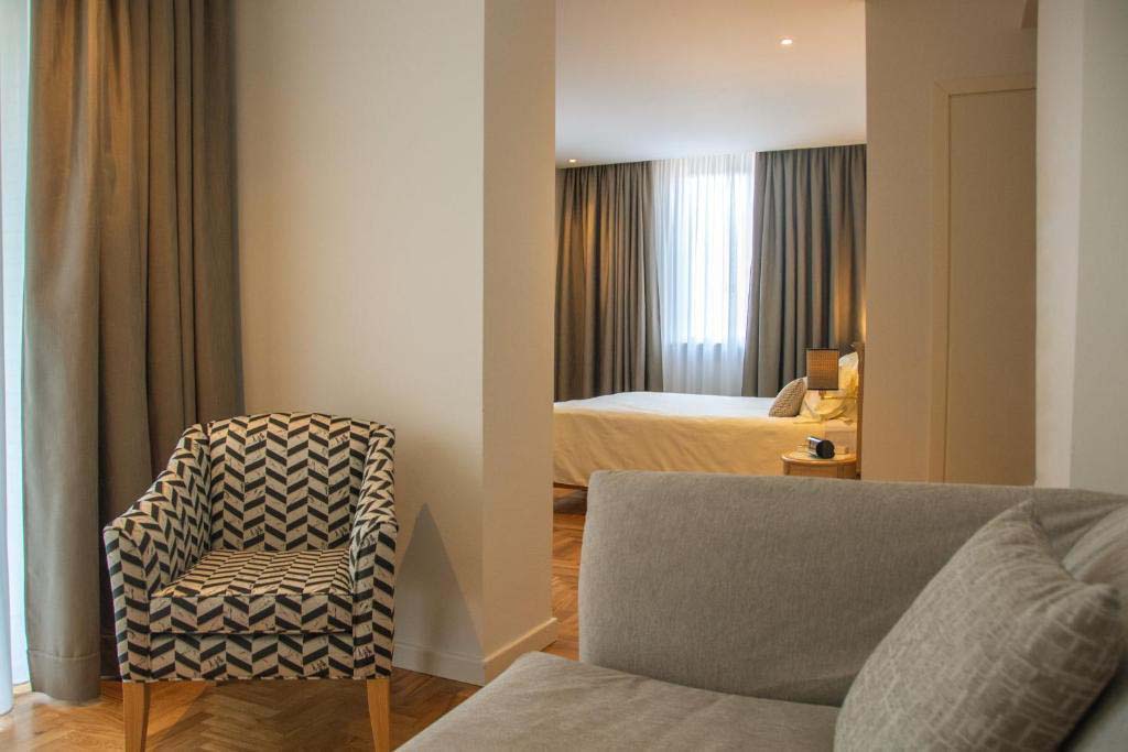 Wohnbereich einer Suite im Ambassador Palace Hotel mit Sofa, Sessel und Blick ins Schlafzimmer.