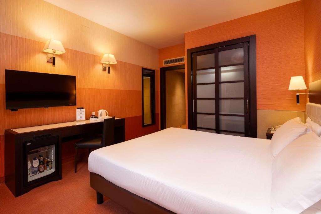 Modernes Hotelzimmer mit Doppelbett, Schreibtisch, TV und Minibar im Best Western Gorizia Palace Hotel.