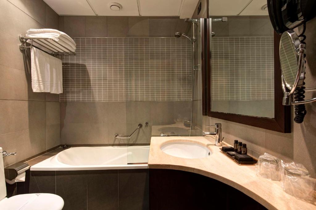 Elegantes Badezimmer mit Badewanne, großem Spiegel und Ablageflächen im Best Western Gorizia Palace Hotel.