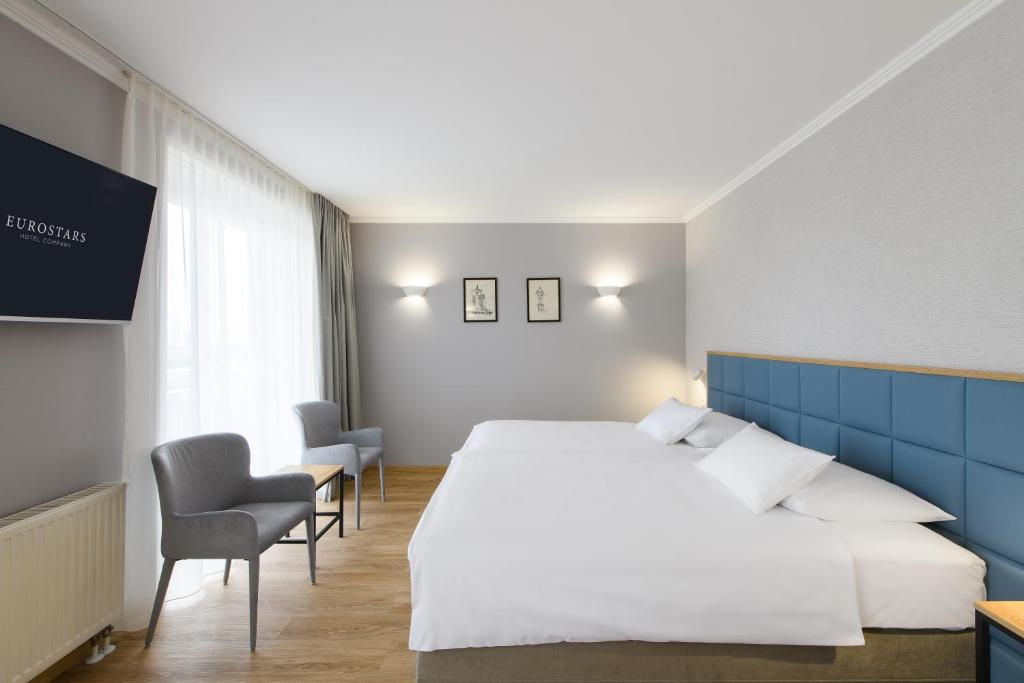 Helles Doppelzimmer im Eurostars uHOTEL Ljubljana mit großem Bett, Sitzbereich und Tageslicht.