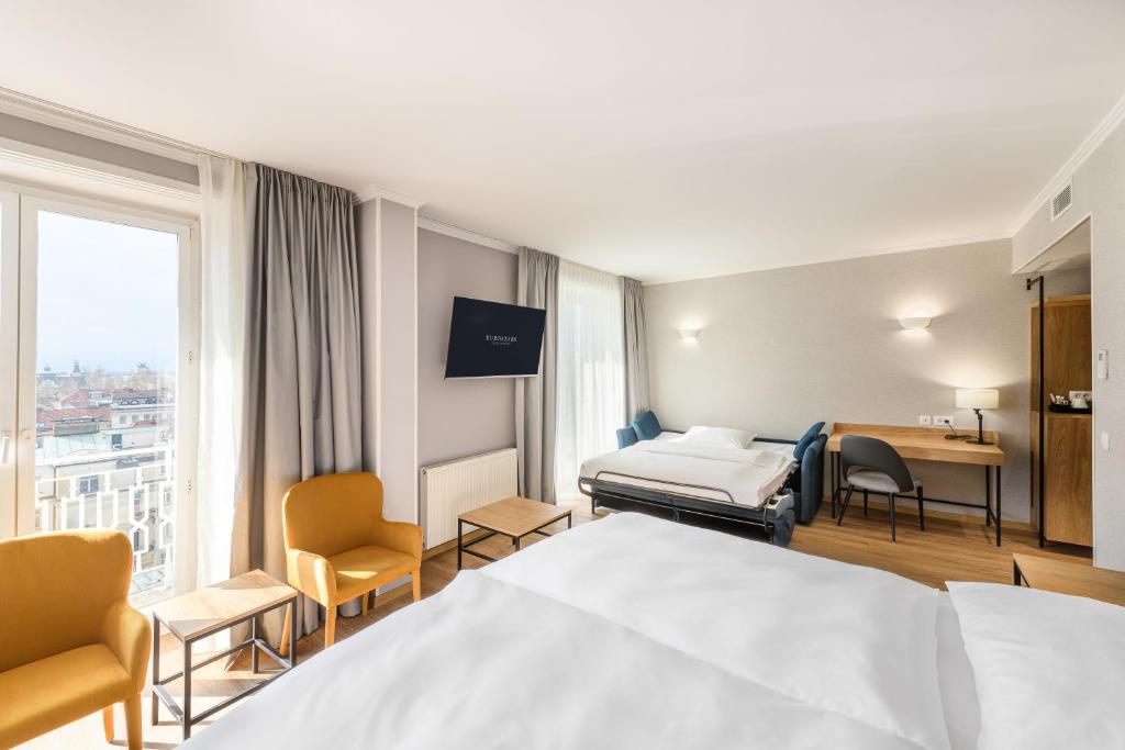 Geräumiges Zimmer im Eurostars uHOTEL Ljubljana mit Schlafbereich, Sofa und Arbeitsbereich.