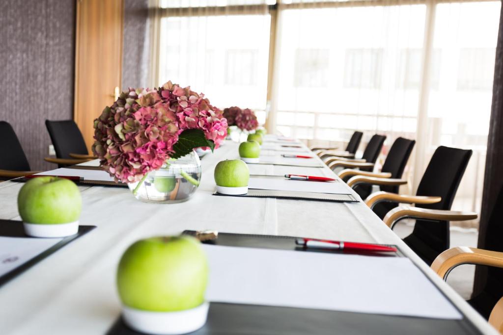 Detailaufnahme eines Konferenztisches im Eurostars UHotel mit Schreibunterlagen, Äpfeln und Blumenarrangement.