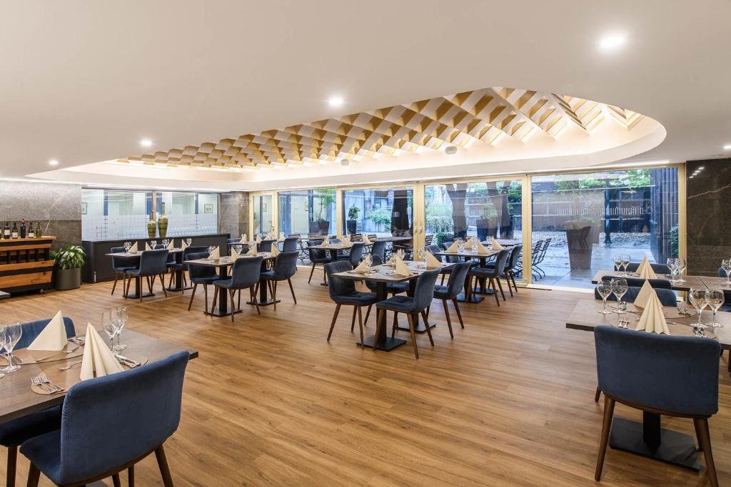 Elegantes Hotelrestaurant im Eurostars uHOTEL Ljubljana mit gedeckten Tischen und Tageslicht.