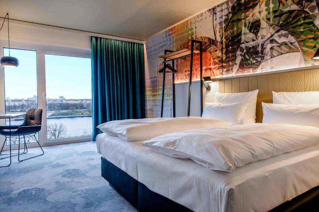 Modernes Hotelzimmer mit Doppelbett, Balkon und Blick auf die Donau im Motel One Wien Donau City.
