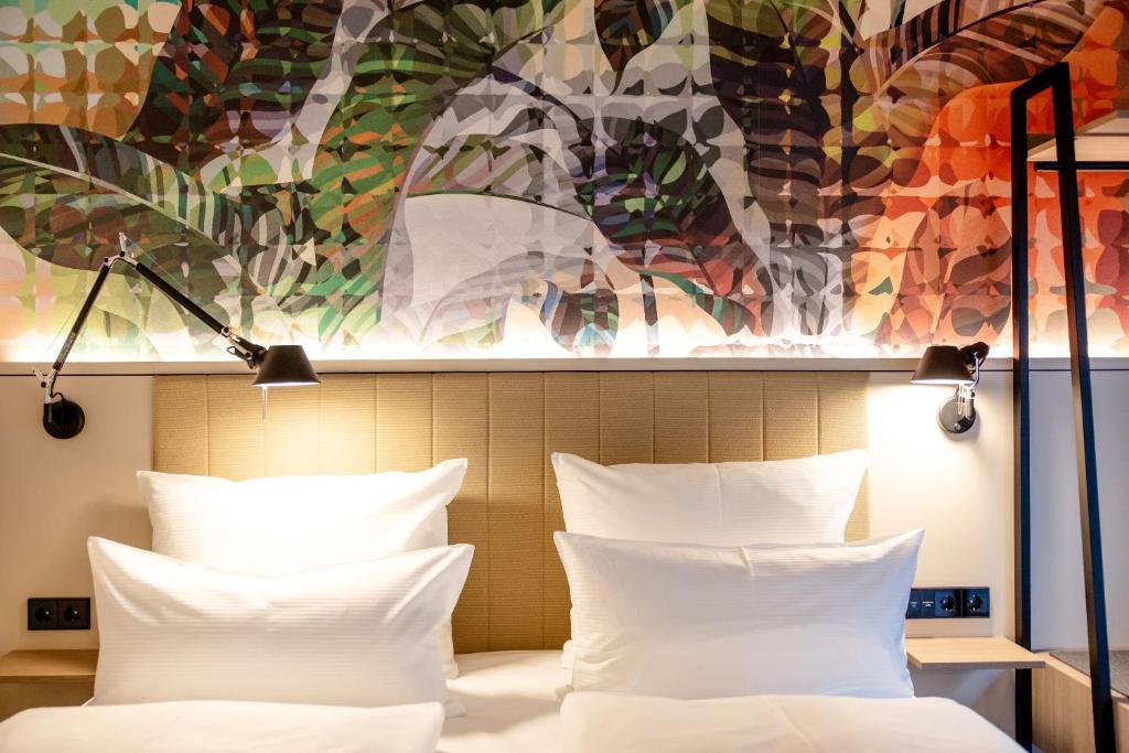 Detailansicht des komfortablen Doppelbetts mit Design-Wandgestaltung im Motel One Wien Donau City.