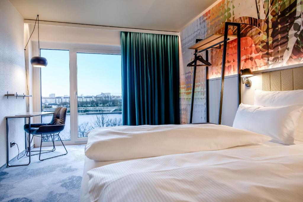 Helles Design-Zimmer mit Balkon, gemütlichem Sitzbereich und Donau-Blick im Motel One Wien Donau City.