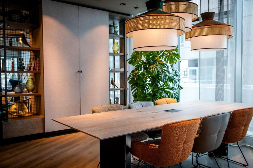 Moderner Meeting- und Arbeitsbereich in einem Designhotel mit großem Konferenztisch, bequemen Stühlen und natürlicher Begrünung.