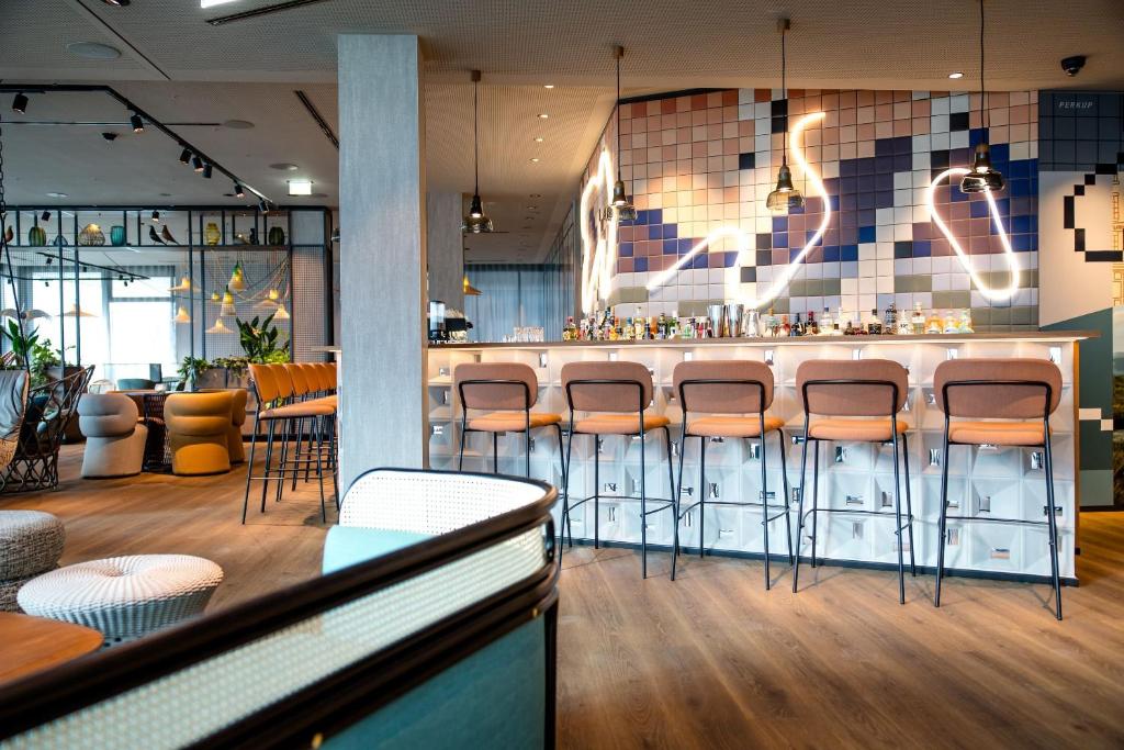 Moderne Hotelbar im Motel One Wien Donau City mit Design-Barhockern, stilvoller Beleuchtung und zeitgemäßem Interieur.