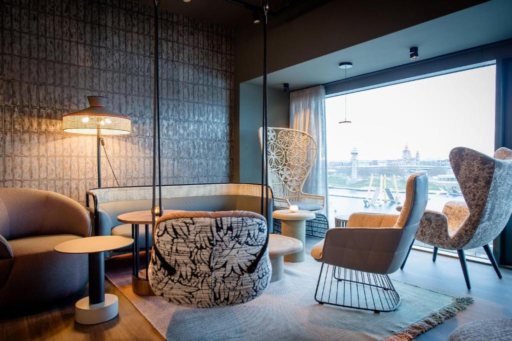 Eleganter Loungebereich im Motel One Wien Donau City mit bequemen Designsesseln und Blick auf die Wiener Skyline.