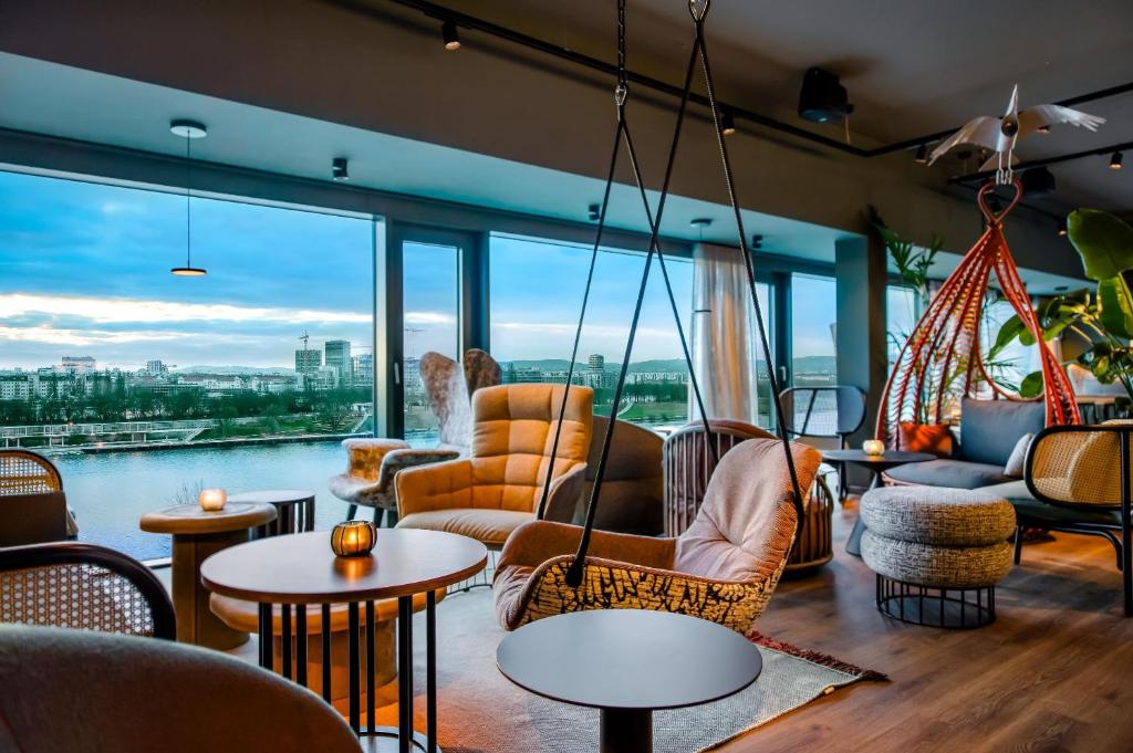 Lounge mit Panoramablick im Motel One Wien Donau City, gemütlichen Hängesesseln und Blick auf die Donau.