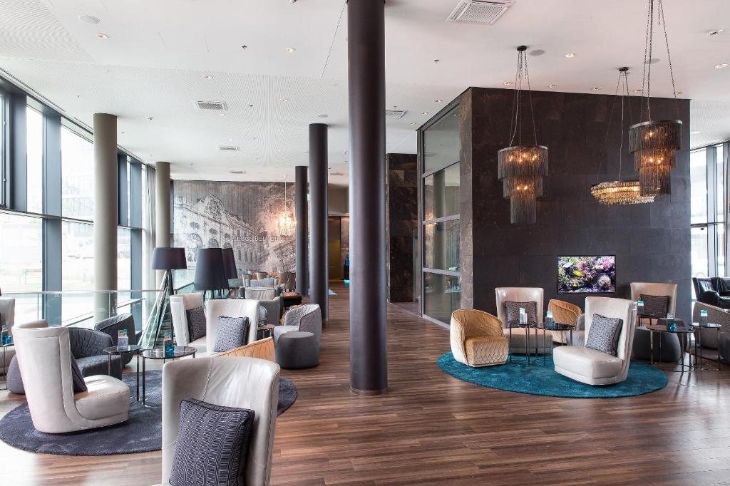 Großer Loungebereich im Hotel Motel One Wien Hauptbahnhof mit Designmöbeln und Säulen.