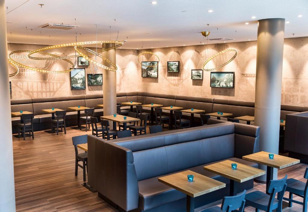 Frühstücksbereich mit Sitzbänken, Holztischen und dekorativer Wandgestaltung im Motel One Wien Hauptbahnhof.