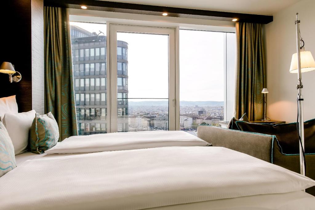Komfortables Doppelzimmer im Motel One Wien Hauptbahnhof mit bodentiefen Fenstern und Blick auf die Wiener Innenstadt.