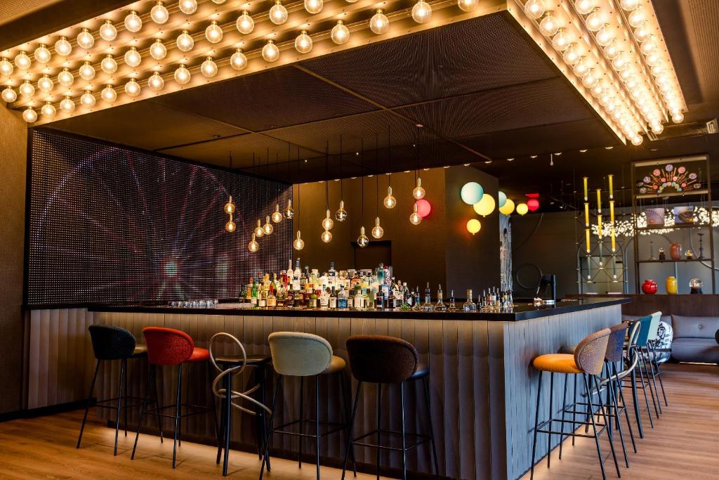 Design-Bar im Motel One Wien Prater mit beleuchteter Theke, Barhockern und stimmungsvoller Lichtinstallation.