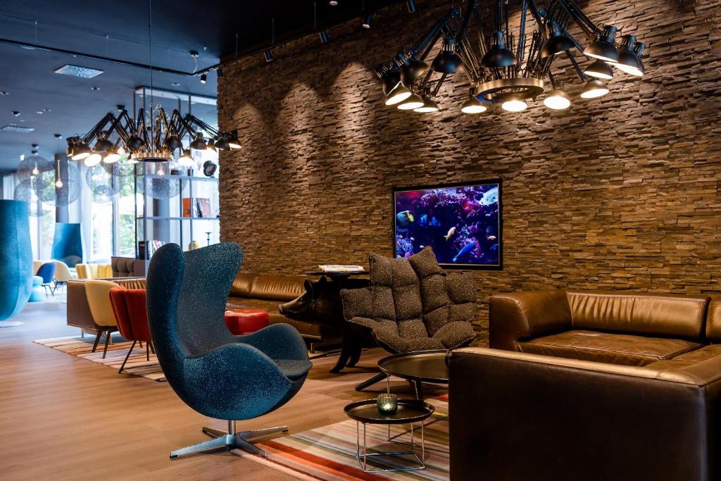 Lounge-Bereich im Motel One Wien Prater mit Ledersofas, Designleuchten und moderner Wandgestaltung.