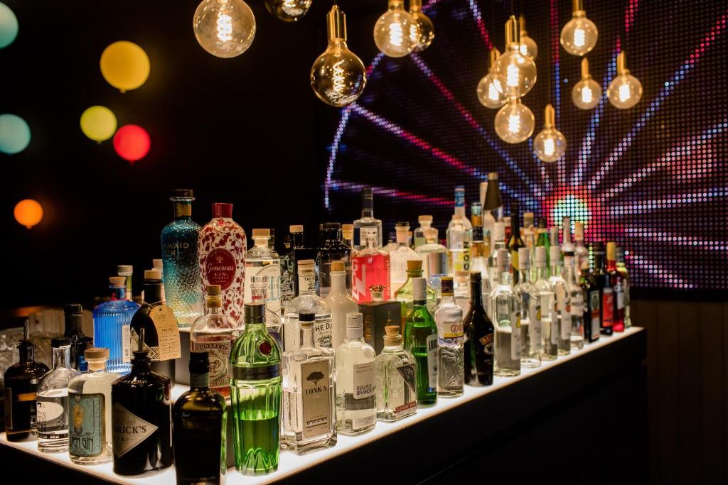 Detailaufnahme der Bar im Motel One Wien Prater mit beleuchteten Flaschen, Designlampen und grafischem Hintergrund.