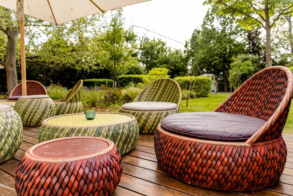 Außenbereich des Motel One Wien Prater mit geflochtenen Lounge-Sesseln, niedrigen Tischen und grünem Gartenambiente.