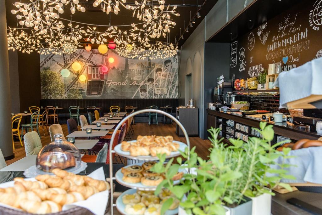 Heller Frühstücksraum im Motel One Wien Prater mit Buffet, Sitzplätzen und stimmungsvoller Beleuchtung.
