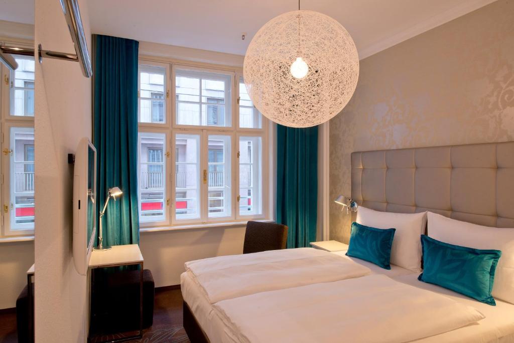Modernes Doppelzimmer im Motel One Wien Staatsoper mit bequemen Betten, großen Fenstern, eleganter Beleuchtung und zentraler Lage in Wien.