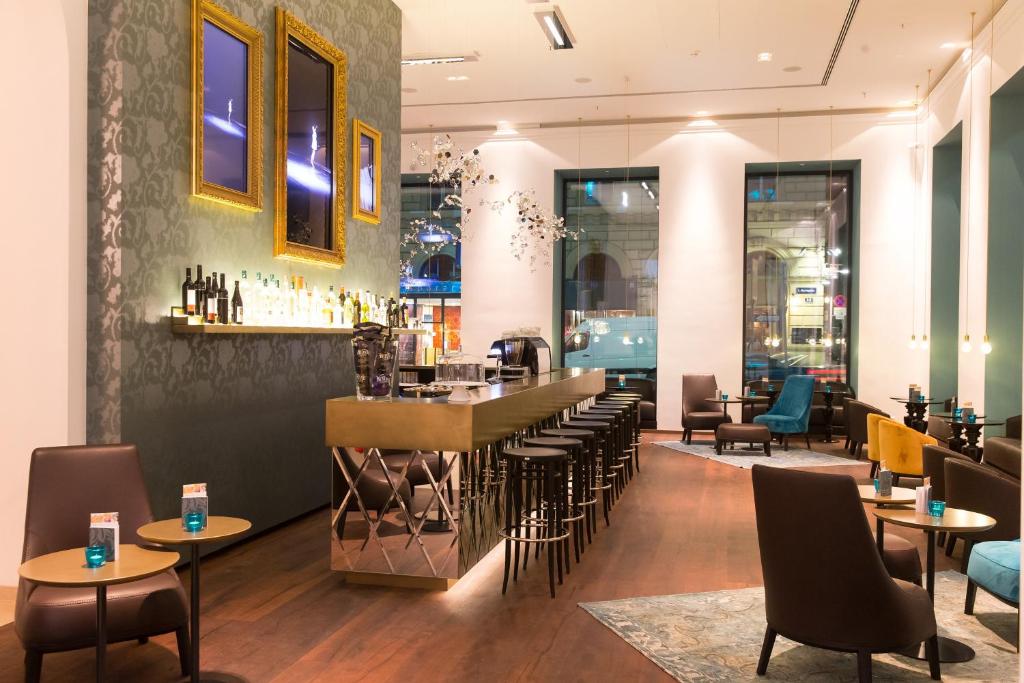 Design-Bar im Motel One Wien Staatsoper mit goldfarbenem Tresen, Barhockern, stilvollen Sitzbereichen und urbanem Ambiente nahe der Wiener Staatsoper.