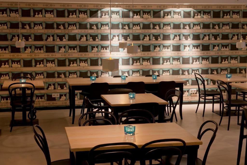 Ruhiger Lounge-Bereich im Motel One Wien Staatsoper mit Tischen, Stühlen und dekorativer Tapete im klassischen Wiener Stil.