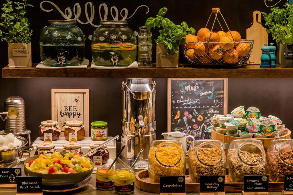 Müsli- und Getränkestation im Motel One Wien Staatsoper mit Cerealien, frischem Obst, Säften und dekorativen Gläsern.