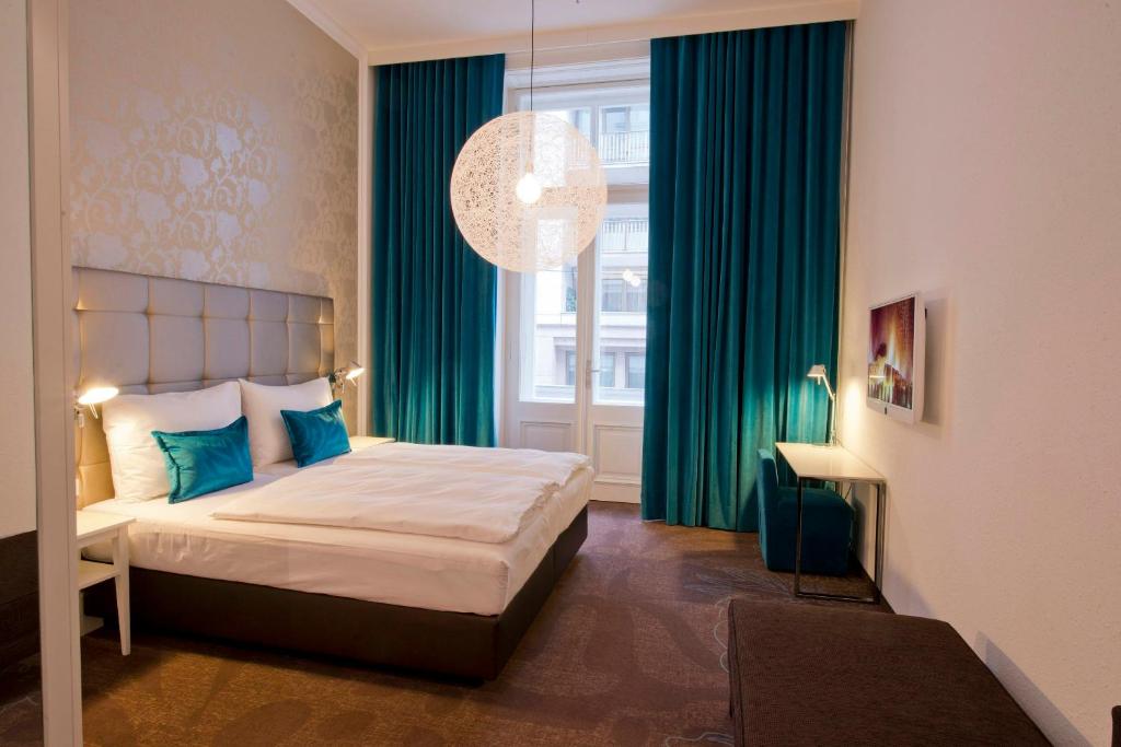 Elegantes Hotelzimmer im Motel One Wien Staatsoper mit Doppelbett, Design-Leuchte, ruhiger Farbgestaltung und zentraler Lage in Wien.