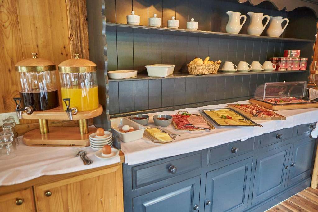 Frühstücksbuffet der Pension Enzian mit regionalen Produkten, Säften, Eiern, Wurst und Käse in gemütlichem Holzambiente.