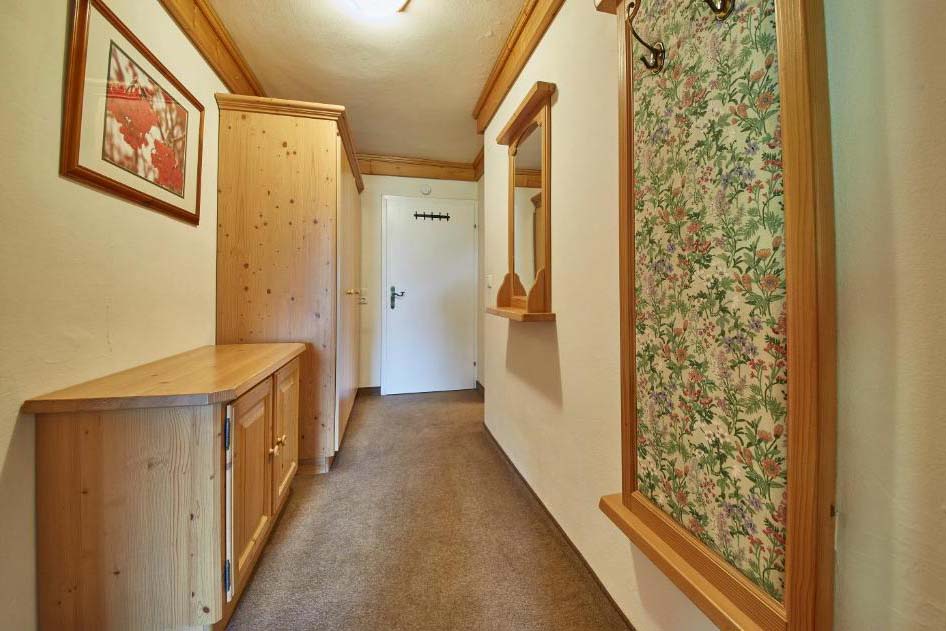 Flur in der Pension Enzian mit Garderobe, Holzmöbeln und traditionellem alpinem Stil.