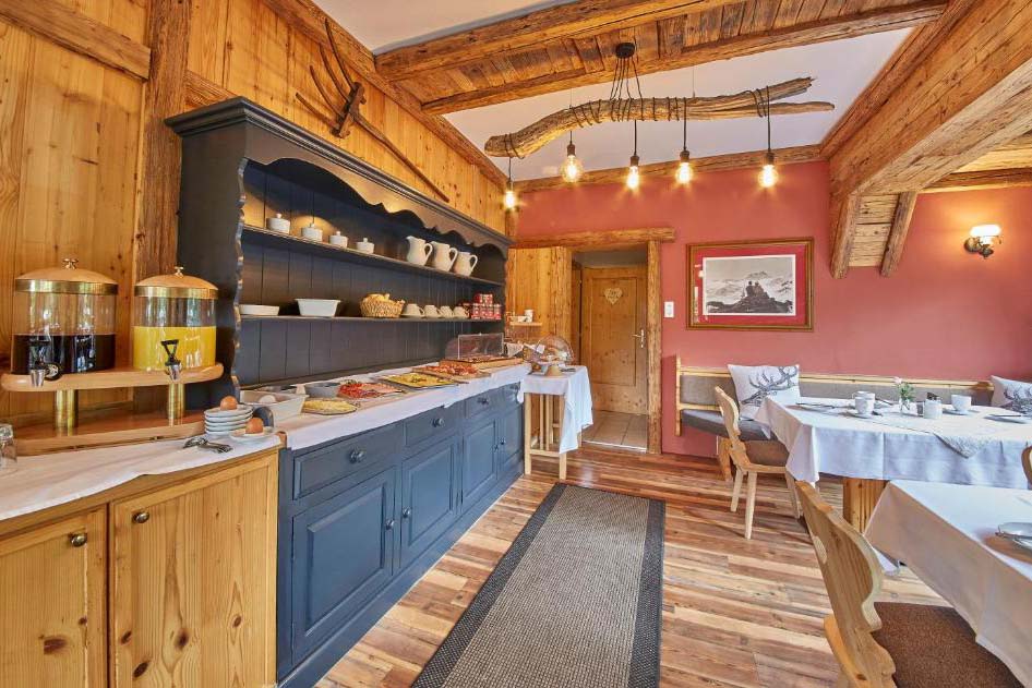 Frühstücksbuffet der Pension Enzian mit regionalen Produkten in rustikalem Holzambiente.