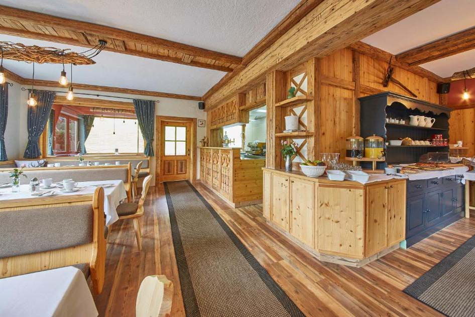 Großzügiger Frühstücksraum der Pension Enzian mit gedeckten Tischen, Holzboden und gemütlicher Atmosphäre.