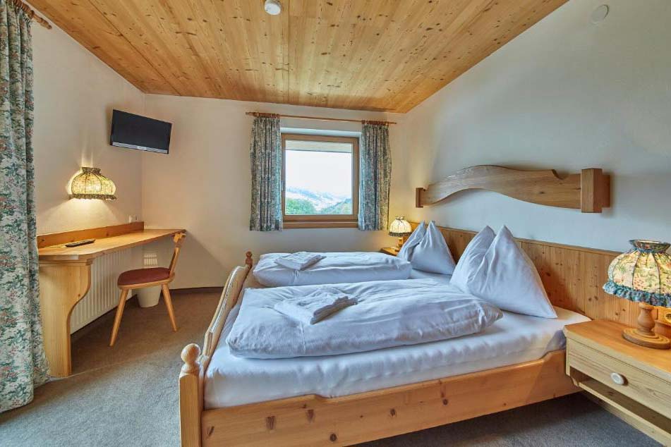 Doppelzimmer in der Pension Enzian mit Schreibtisch, Holzmöbeln und ruhiger Lage.
