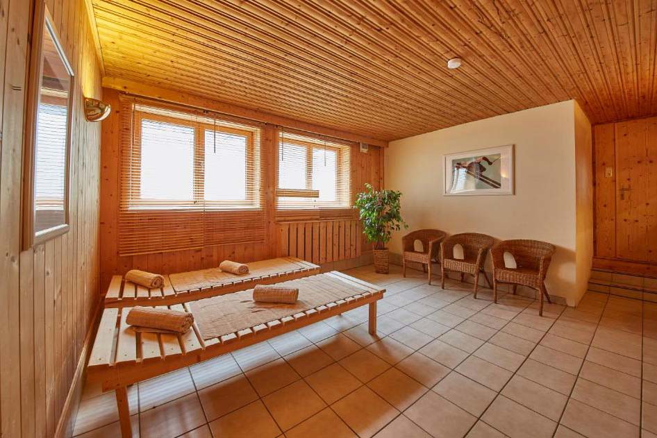Gemütlicher Ruheraum mit Holzliegen und Handtüchern im Wellnessbereich der Pension Enzian – ideal zum Entspannen nach Sauna oder Skitag.
