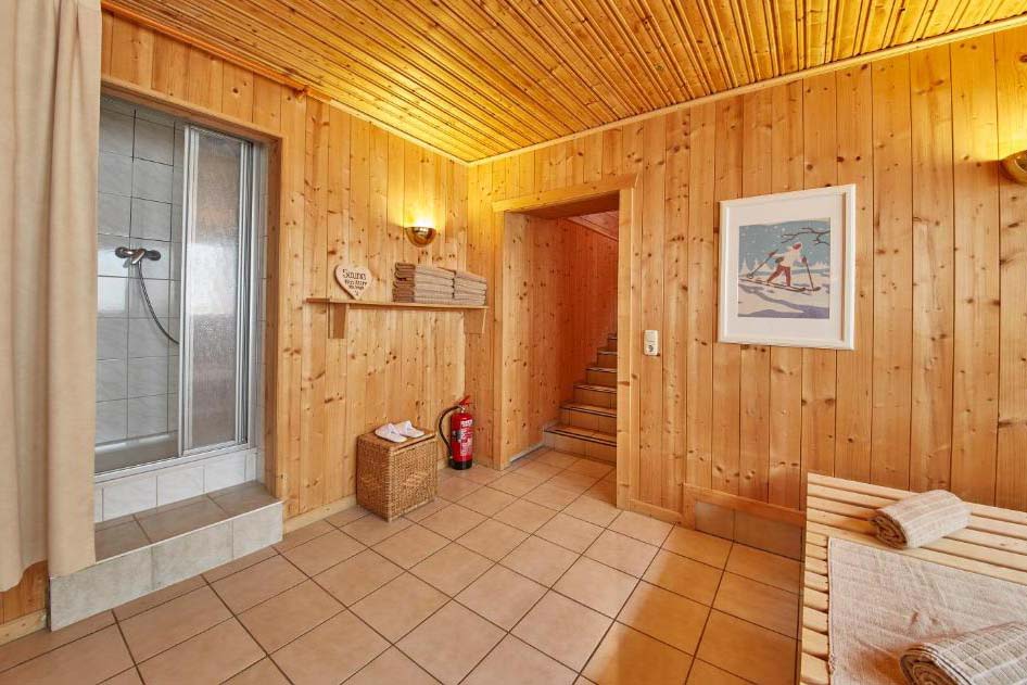 Wellnessbereich der Pension Enzian mit Dusche, Holzverkleidung und direktem Zugang zum Saunabereich.