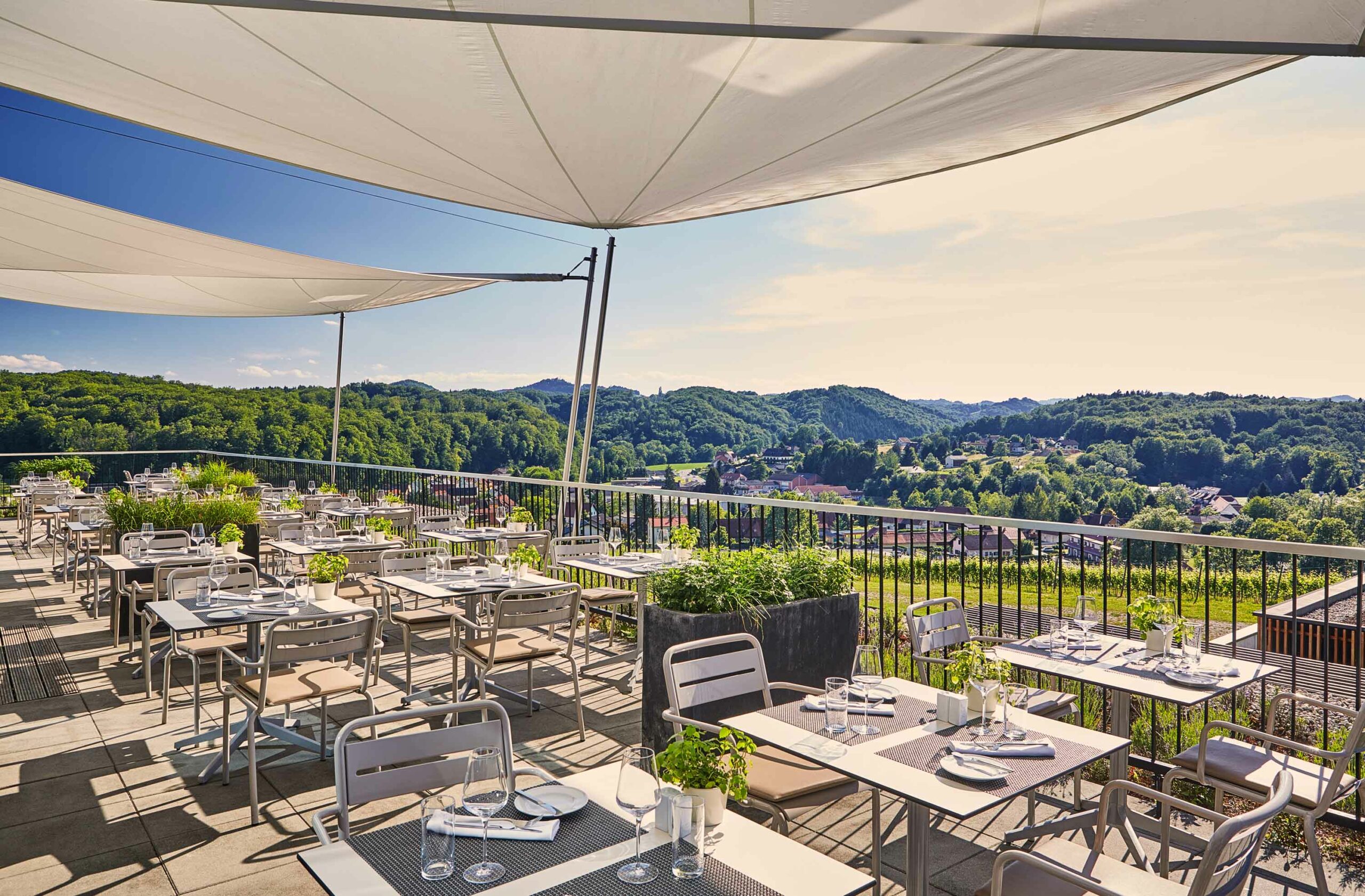 Restaurantterrasse im LOISIUM Südsteiermark mit gedeckten Tischen und Panoramablick über die Weinregion.
