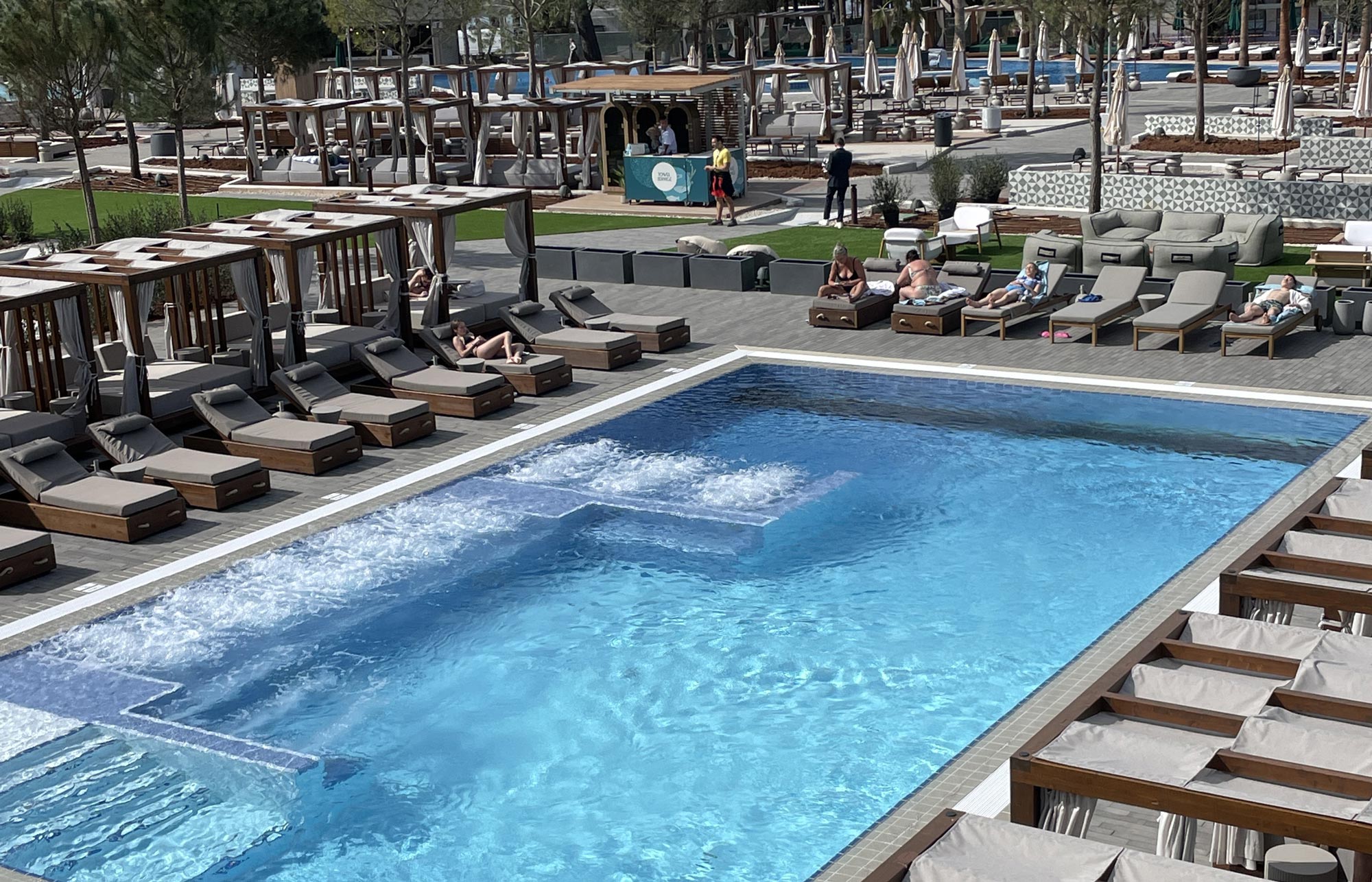 Moderne Poolanlage mit Liegen, Cabanas und entspannter Atmosphäre in einem Resort an der Adriaküste.