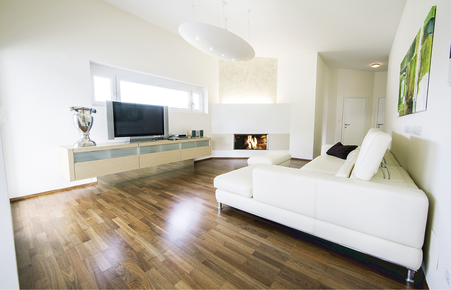 Moderner Wohnraum mit weißem Ecksofa, Wandregal mit Fernseher und Kamin in einer hellen Wohnung