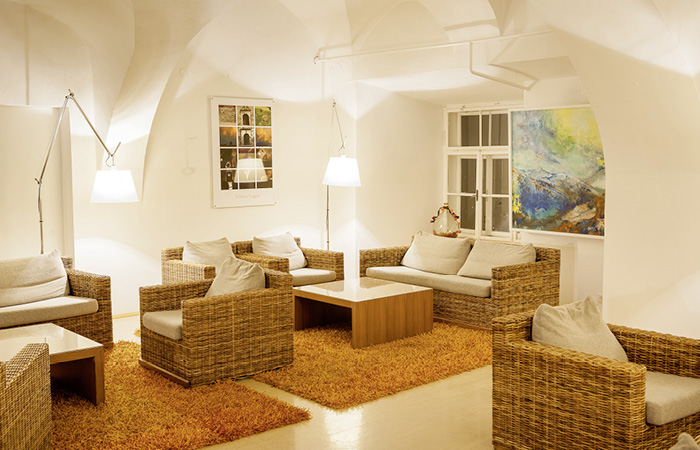 Gemütlicher Sitzbereich mit Rattansesseln und Sofas um niedrige Tische in einem Raum mit gewölbter Decke